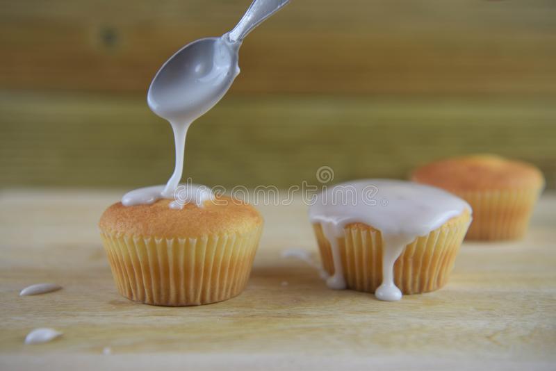 Pouring frosting over cupcakes